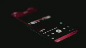 A smartphone screen in a dark setting displays the Spotify music player interface with a song titled "LoveYou" currently playing.