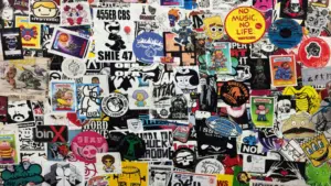 A wall densely covered with assorted colorful stickers, featuring various characters, logos, trademark slogans, and artistic designs overlapping each other.