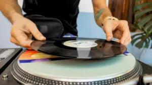 A person places a vinyl record onto a turntable, preparing to enjoy the warm sound of analog music.