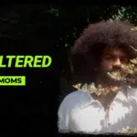 A person with a large afro stands partially behind leafy branches; text reads "Symphonic Unfiltered with Webmoms." The scene highlights an unfiltered vibe, blending natural elements with authentic energy.