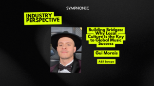 A man in a tuxedo and hat is pictured next to text about building bridges in music and achieving global music success, featuring Gui Morais, A&R Europe, as part of an "Industry Perspective" by Symphonic.
