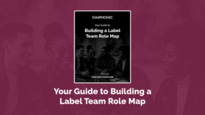 A group of four people sit and talk together. Text on the image reads: "Your Guide to Building a Label Team Role Map"—perfect for anyone looking to define label roles and responsibilities.