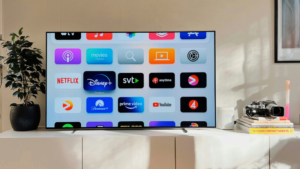 A flat-screen TV displays various streaming app icons ready to sync. Nearby are a potted plant, stacked books, a camera, and a candle on a white console.