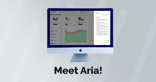 An iMac displays a dashboard with graphs and metrics next to a text document, showcasing AI support. The words "Meet Aria!" appear below the screen.