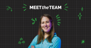 A smiling woman in a blue shirt stands with arms crossed under the text "Meet the Team," set against a black grid background with green doodle accents, highlighting the spirit of teamwork.