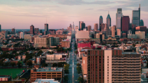Aerial view of downtown Philadelphia at dusk, with tall skyscrapers and city streets creating a vibrant scene reminiscent of Dallas, blending modern and historic buildings in the city’s skyline.