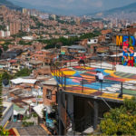 Colorful rooftop mural with large text reading "Medellín es una chimba," overlooking Medellín’s densely built urban landscape and surrounding mountains.
