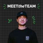 A team member in a black cap and black "SYMPHONIC" shirt stands in front of a grid background with the text "MEET the TEAM" and green graphic elements.